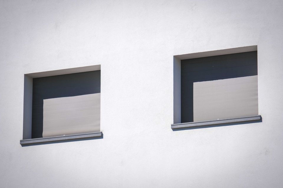 Volets roulants gris sur façade blanche